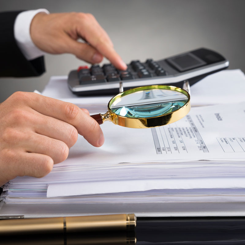 businessperson-checking-invoice-with-magnifying-glass
